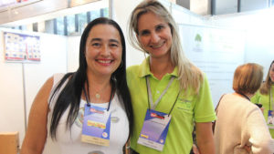 Duas participantes em um estande de exposição.